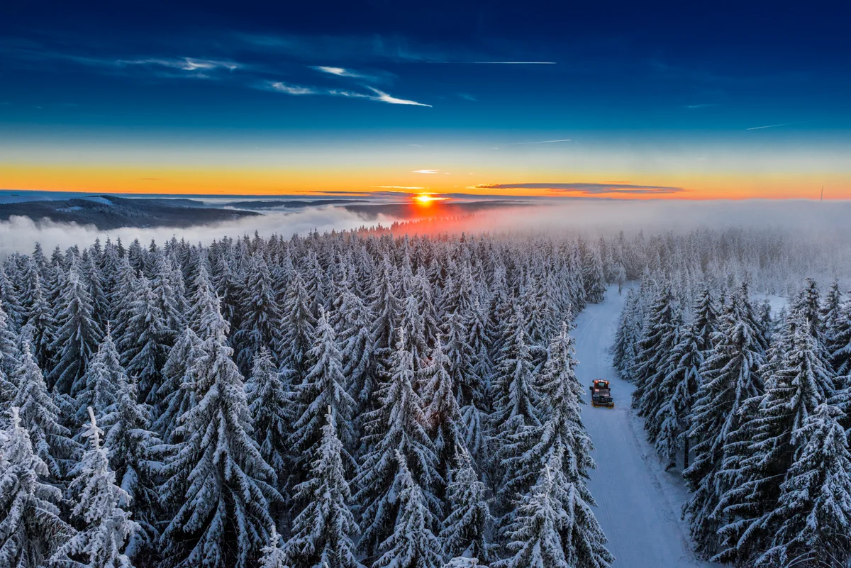 Verschneiter Thüringer Wald mit präparierter Strecke im Sonnenaufgang